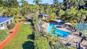 A resort with a swimming pool, lounge chairs, and a tennis court. - Korora Bay Village Resort (Korora)