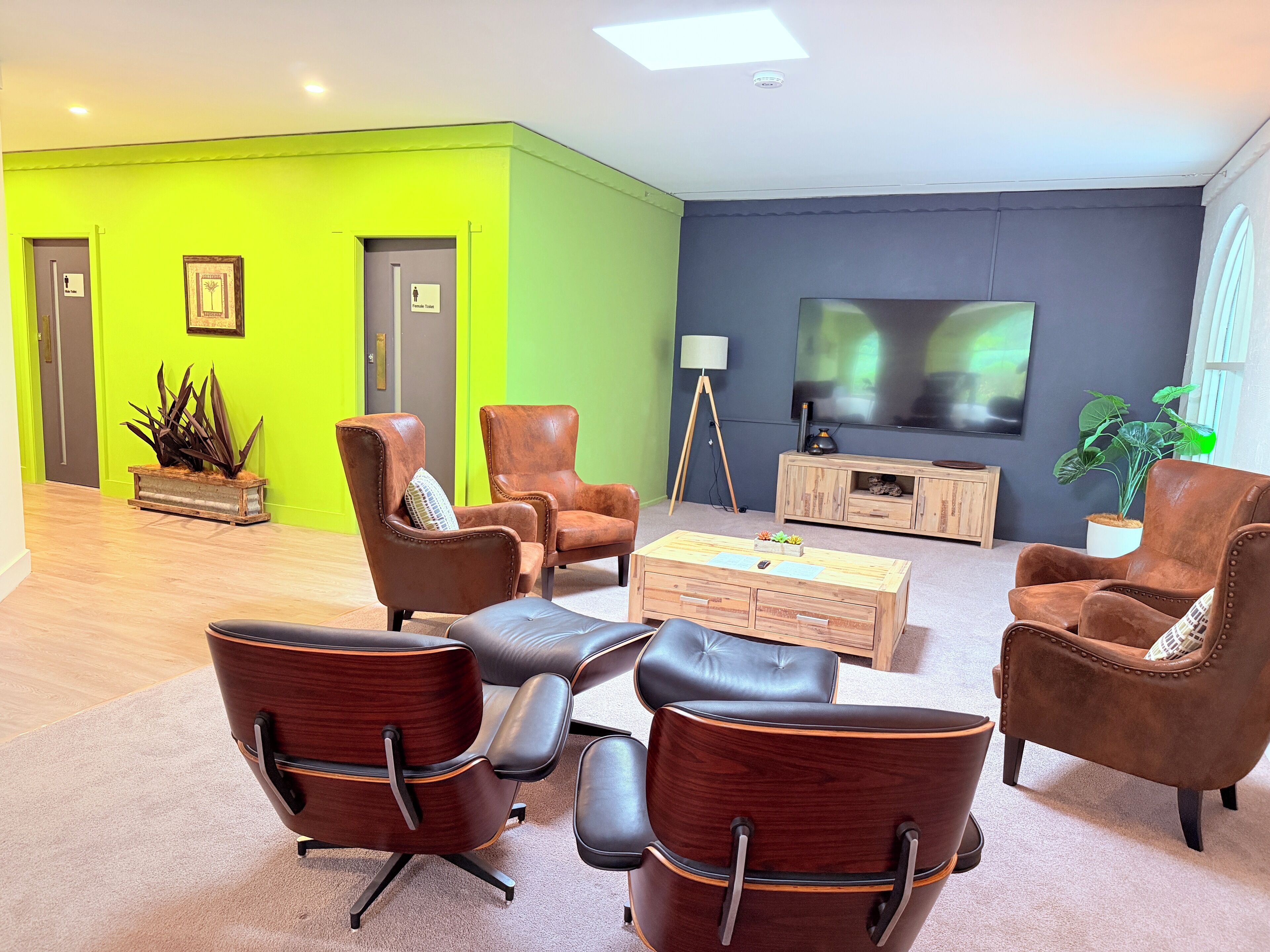 Una sala de estar moderna con sillones de cuero, una mesa de centro de madera y un televisor de pantalla plana montado en la pared.