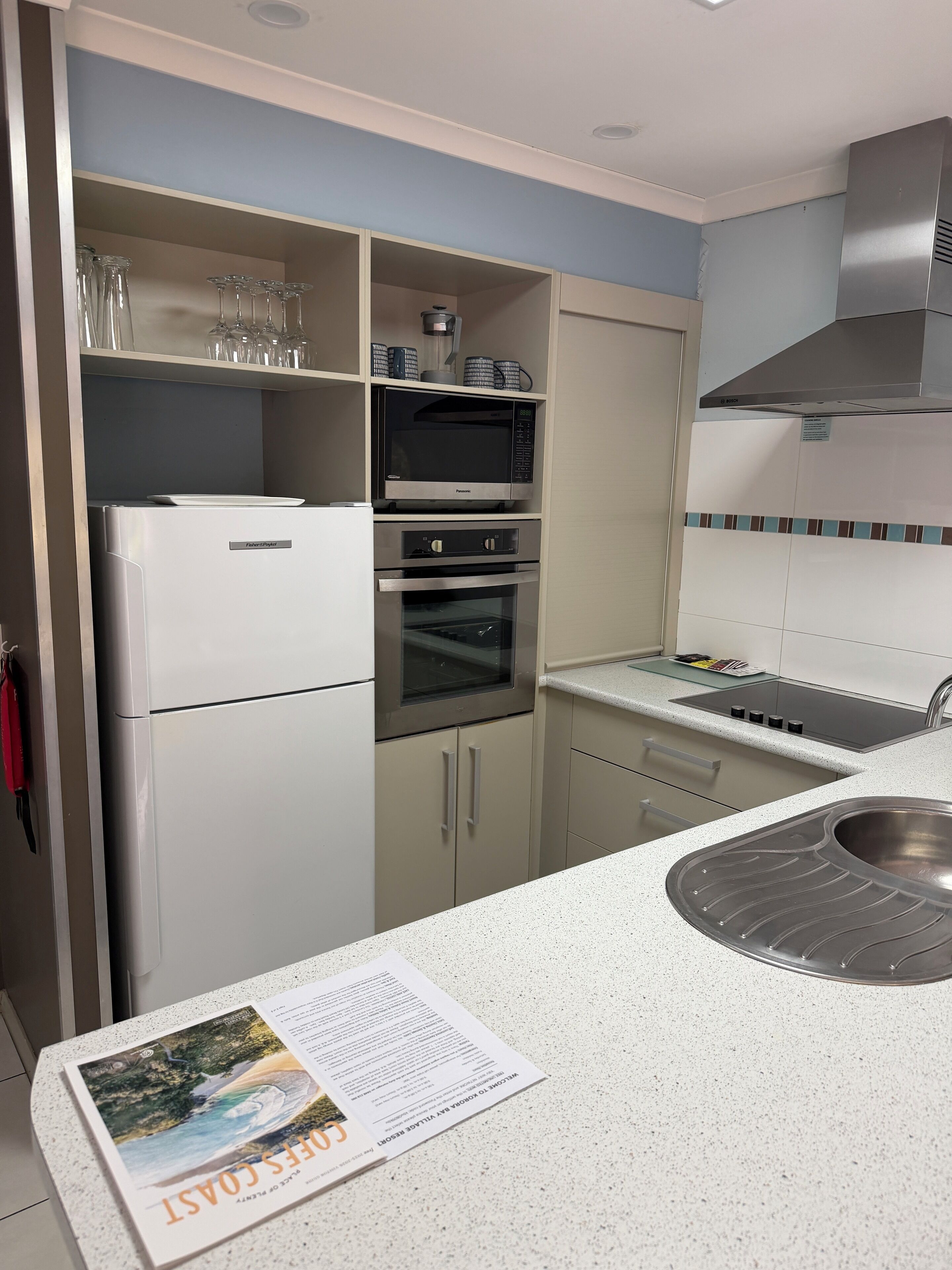 Cocina moderna con refrigerador, horno, microondas y pileta de acero inoxidable.