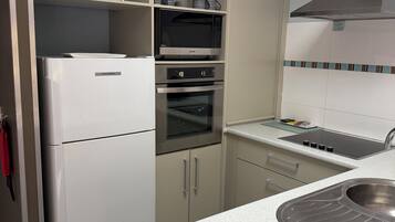 Cocina moderna con refrigerador, horno, microondas y pileta de acero inoxidable.