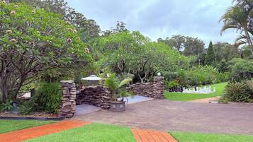 A landscaped garden with a stone archway, a paved walkway, and various greenery.