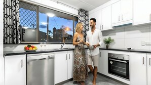 Amplio apartamento con cocina completa, armarios blancos, lavavajillas, horno y ventana con vistas a edificios.