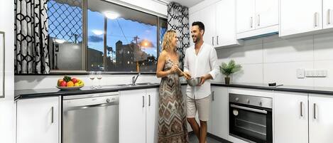 Amplio apartamento con cocina completa, armarios blancos, lavavajillas, horno y ventana con vistas a edificios.
