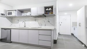 Una cocina moderna con armarios blancos, un lavamanos doble y un microondas.
