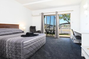 Una habitación de hotel con cama, escritorio y balcón con mesa y sillas.