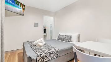 A modern hotel room with a bed, a desk, and a chair.