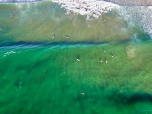 Vista aérea de uma área costeira com águas turquesas cristalinas e uma praia arenosa.
