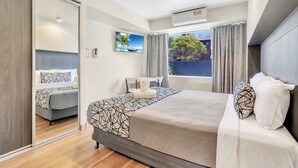 A modern hotel room with a large bed, a desk, and a view of the outdoors. - Surf Beach Motel Port (Port Macquarie)