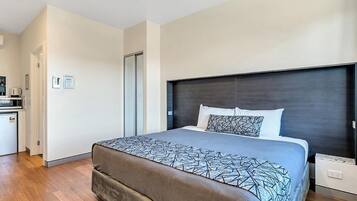 Un dormitorio moderno con una cama grande, un cabecero oscuro y suelo de madera.