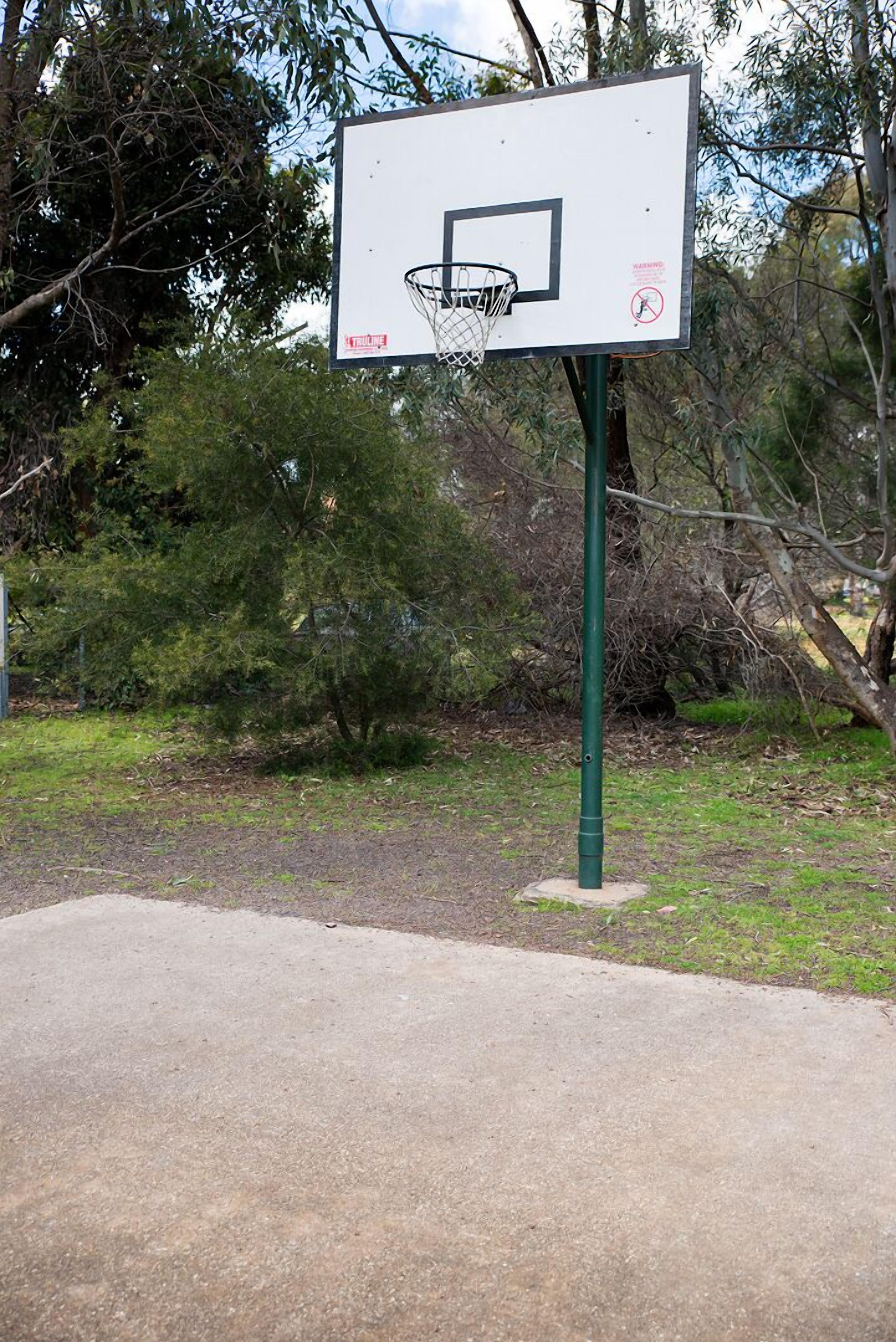 Una cancha de baloncesto con aro y un letrero que indica que no se permite practicar skate.
