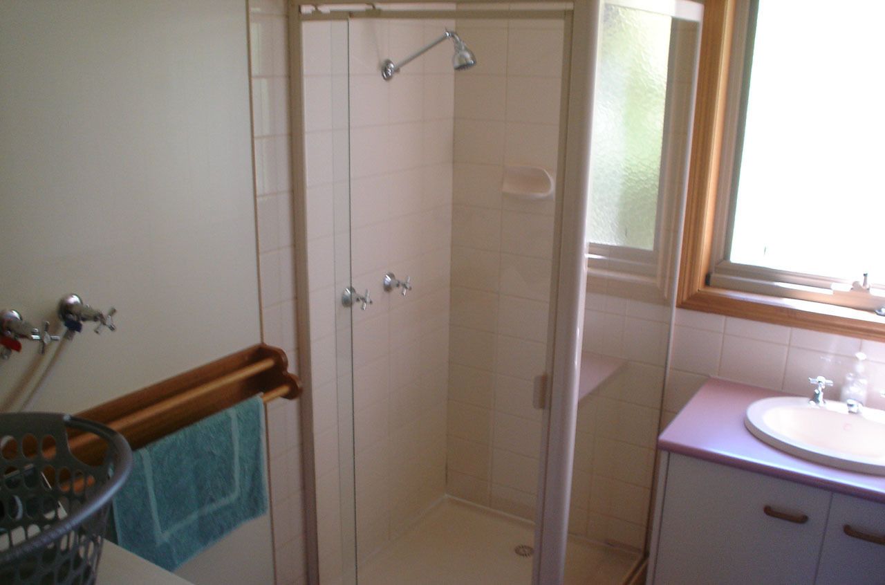 A bathroom with a shower, a sink, and a window.