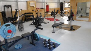 Uma academia com diversos equipamentos de exercícios, incluindo esteira, bicicleta ergométrica e aparelhos de musculação.