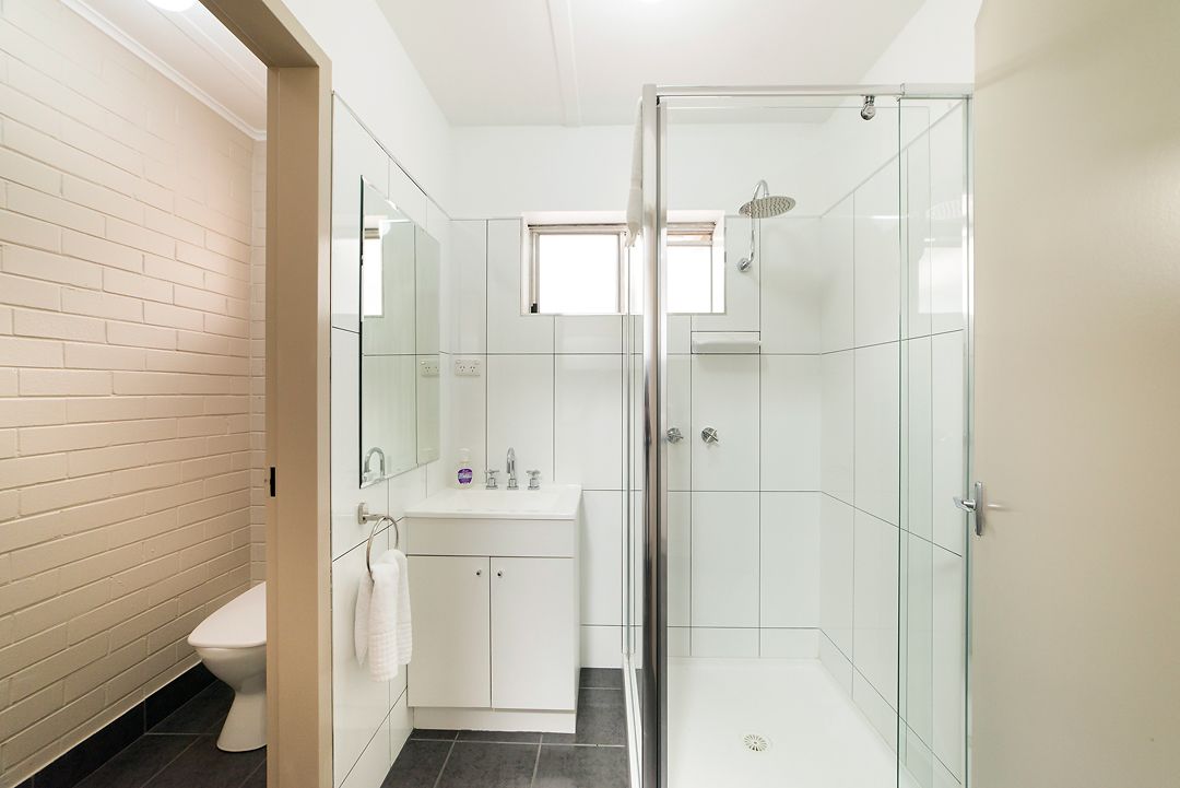A modern bathroom with a glass shower enclosure, a white sink, and a toilet.