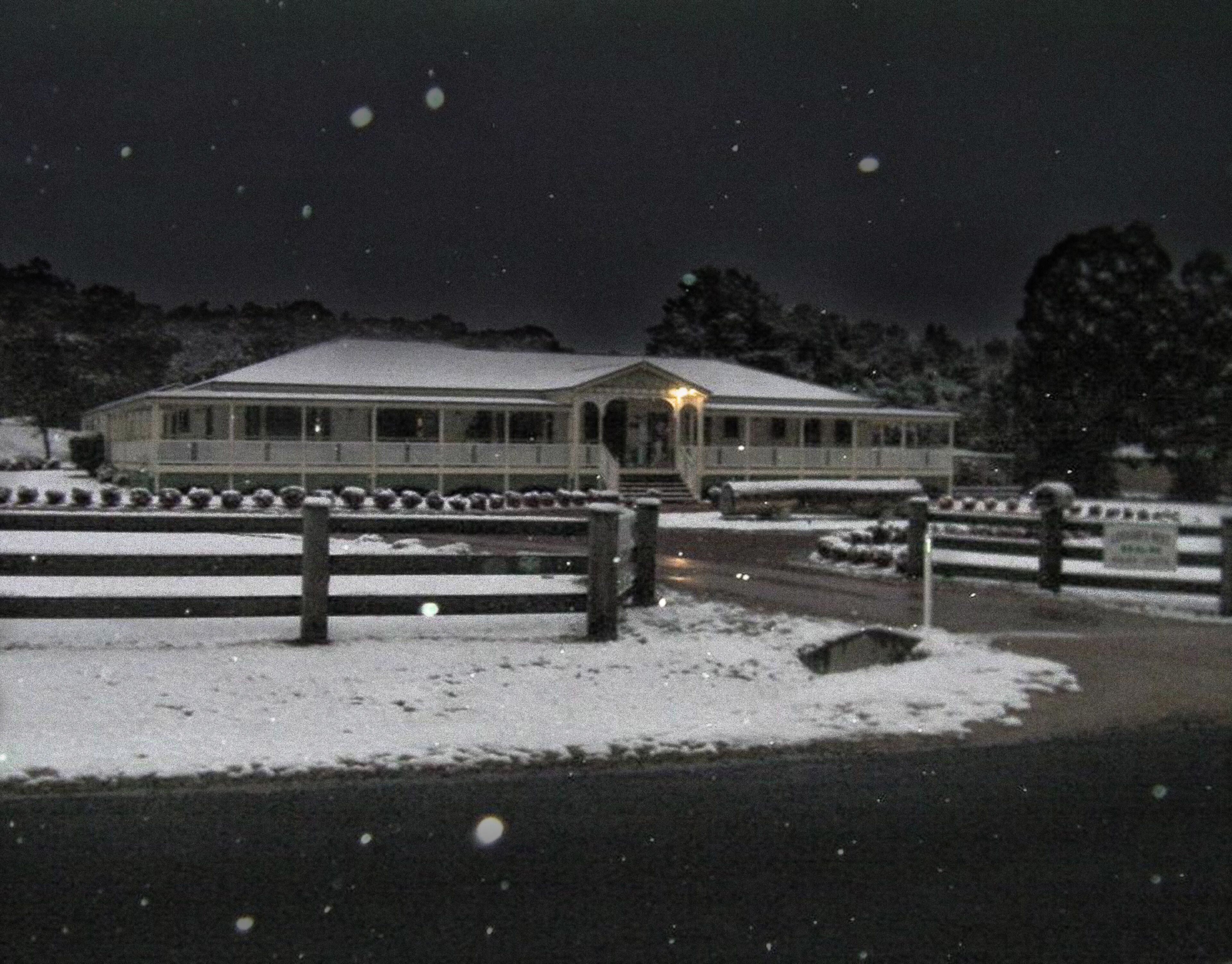 A large, illuminated building with a snow-covered landscape.