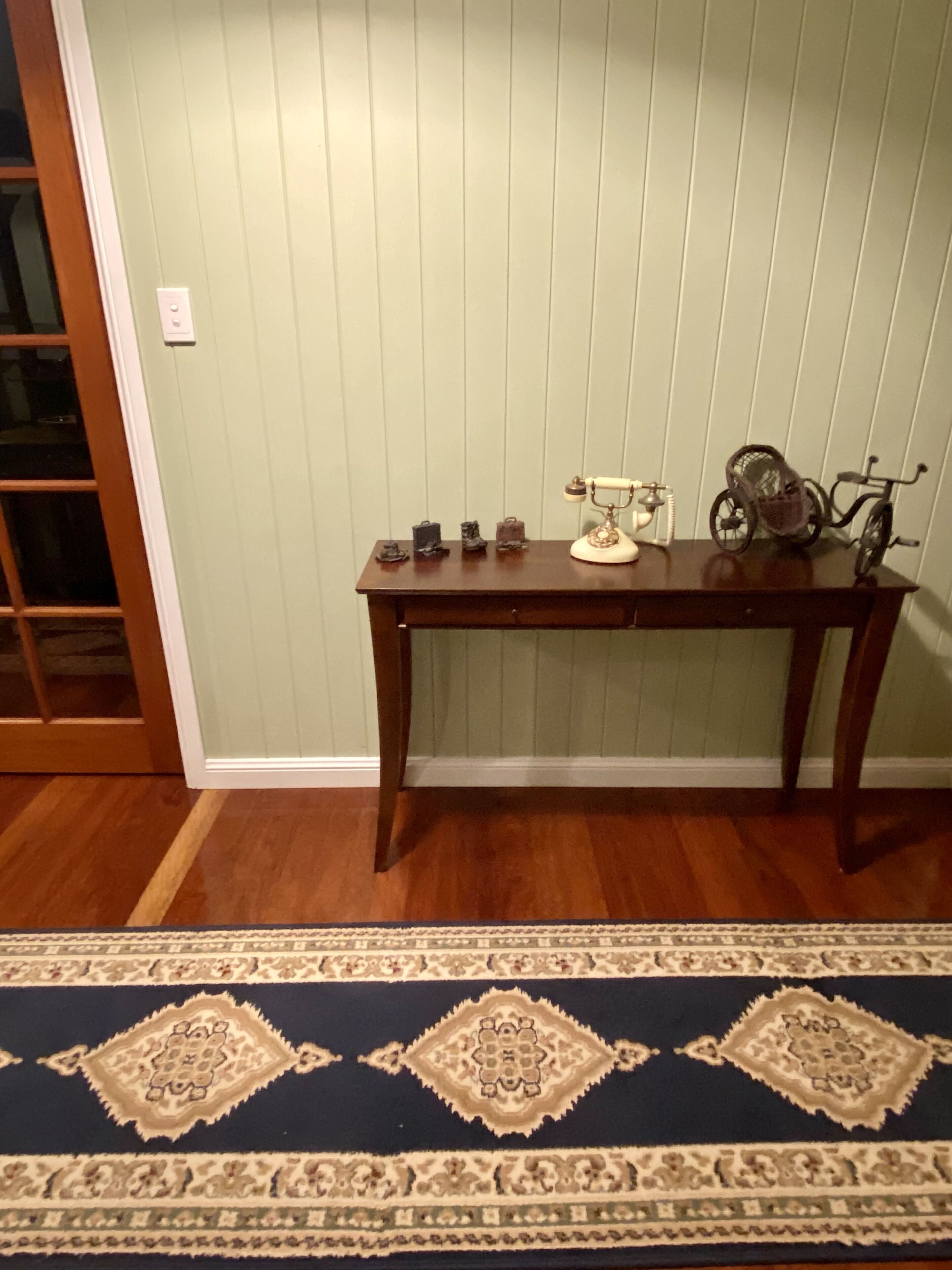 Una habitación con una mesa de madera, una máquina de escribir antigua y un tapete estampado.