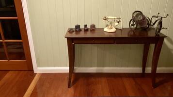 Una habitación con una mesa de madera, una máquina de escribir antigua y un tapete estampado.