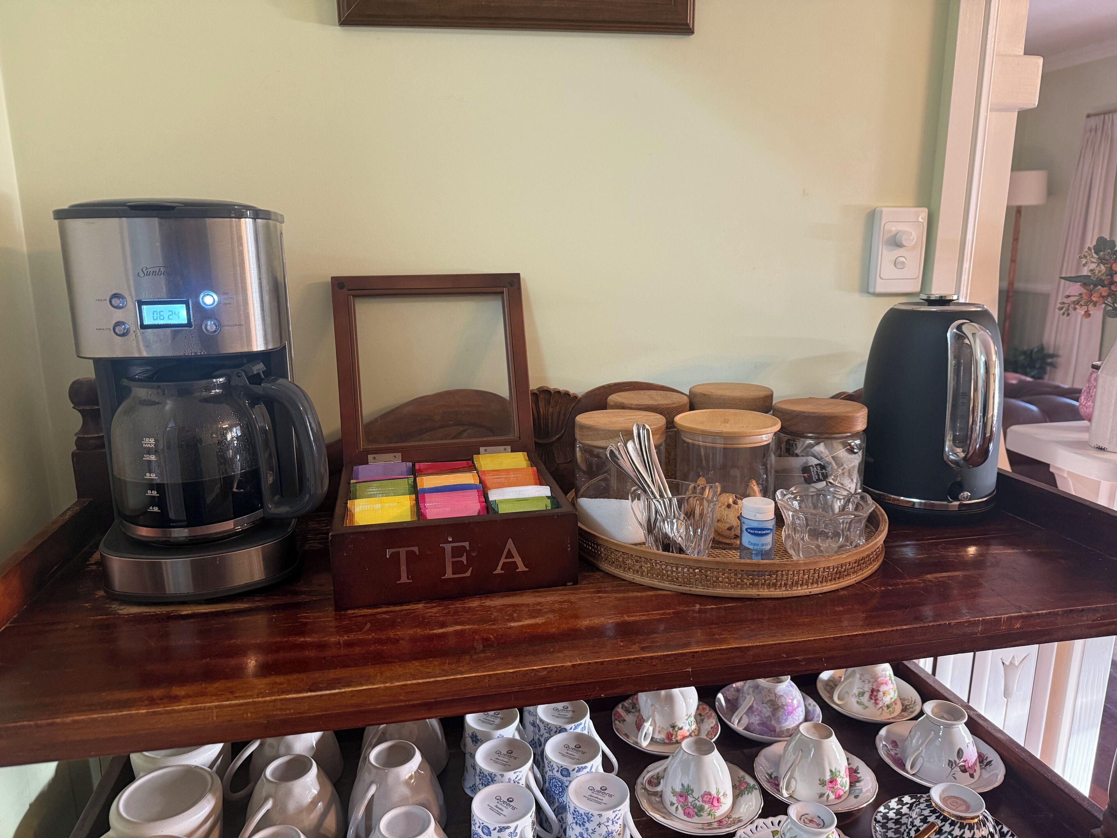 Una estación de café con cafetera, cajas de té y una bandeja para té.