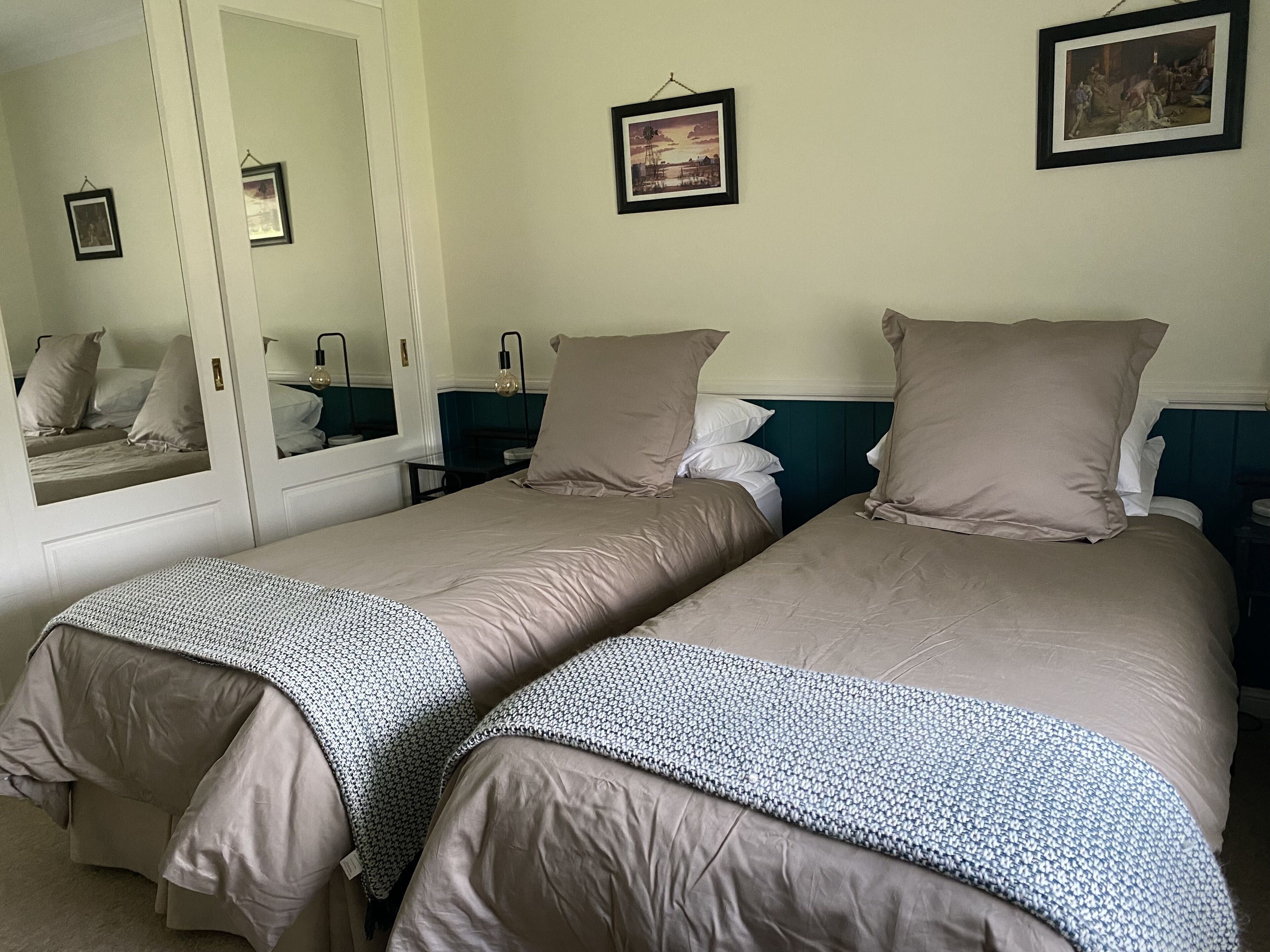 A hotel room with two beds, a large mirror, and a framed picture on the wall.