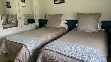 A hotel room with two beds, a large mirror, and a framed picture on the wall.