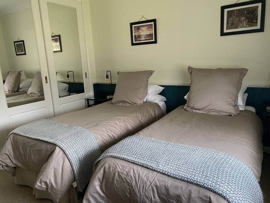 A hotel room with two beds, a large mirror, and a framed picture on the wall.