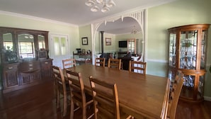 Comedor con una gran mesa de madera y sillas, una araña y un aparador de vidrio con vajilla.