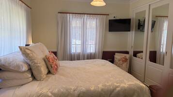 A hotel room with a large bed, a television mounted on the wall, and a wardrobe with a mirror.