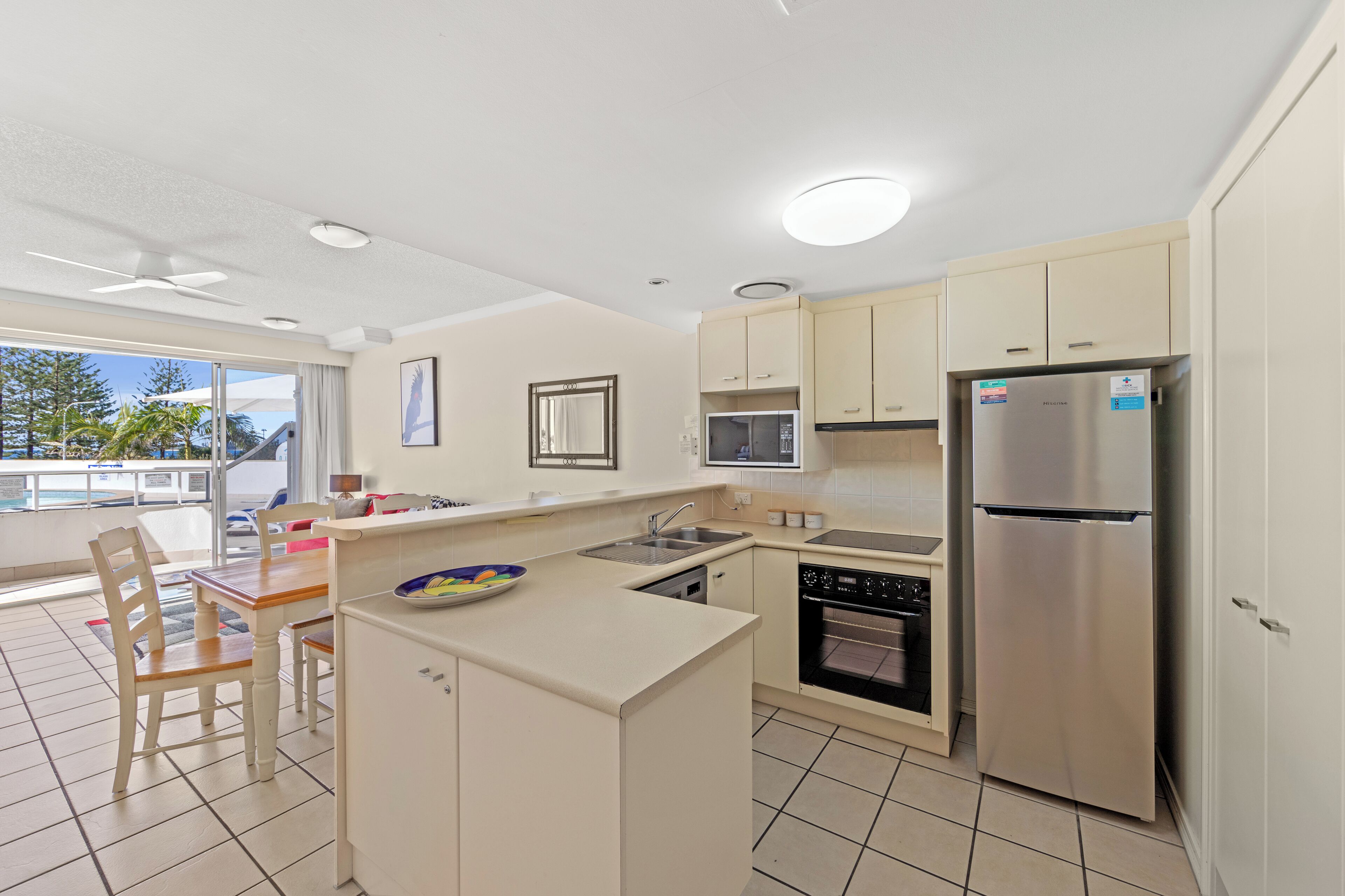 A modern kitchen with a central island, built-in oven, microwave, and stainless steel refrigerator.