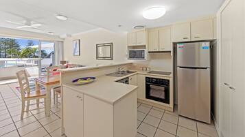 A modern kitchen with a central island, built-in oven, microwave, and stainless steel refrigerator.