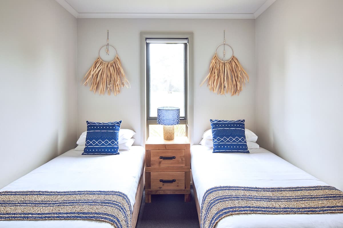 Ein Zimmer mit zwei Betten, einem Nachttisch aus Holz mit Schubladen und einem Fenster mit Blick.