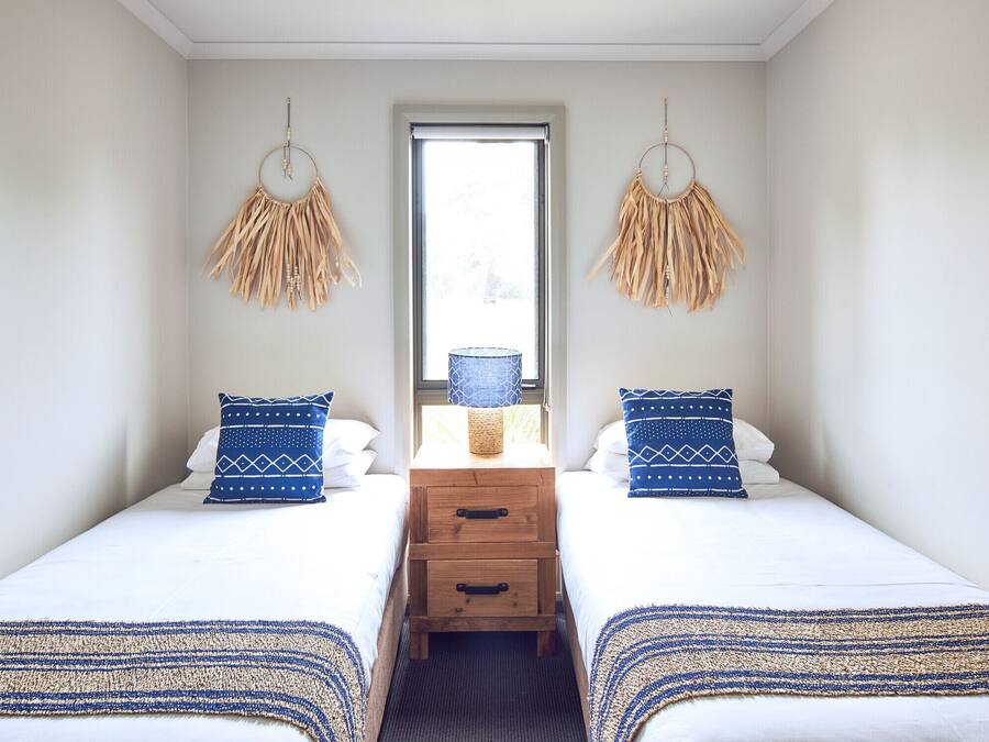 A room with two beds, a wooden nightstand with drawers, and a window with a view.