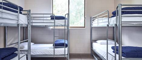 A dormitory room with bunk beds, a window with a view, and an air conditioning unit.