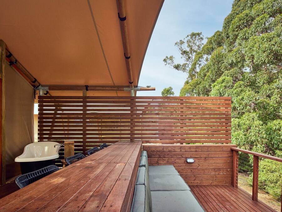 Een terras buiten met een houten tafel, stoelen en een ingebouwde bank.