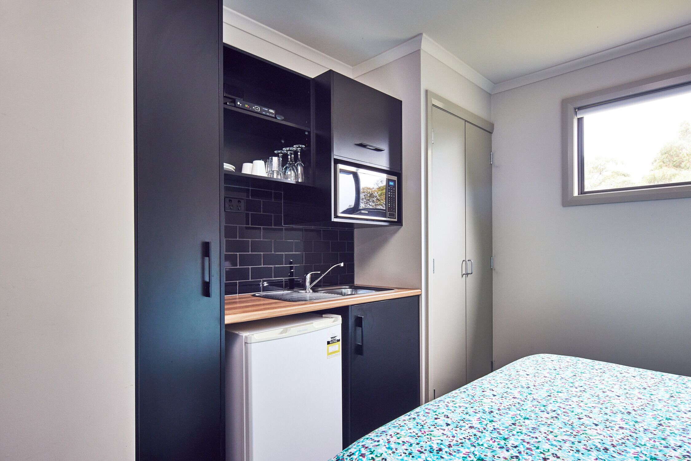 A compact kitchen with a microwave, sink, and small refrigerator.