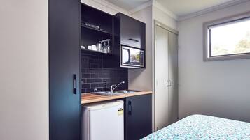 A compact kitchen with a microwave, sink, and small refrigerator.