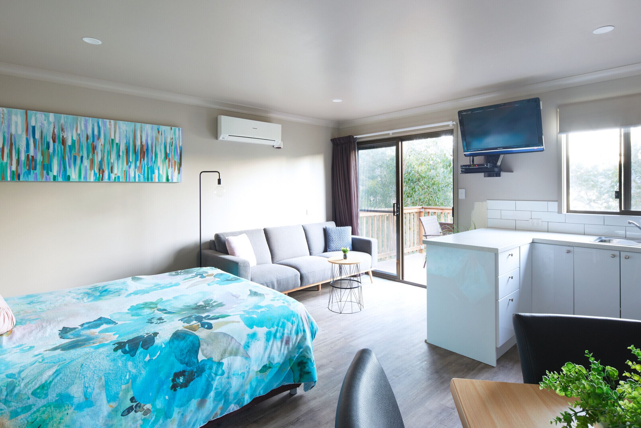 A modern room with a bed, sofa, dining table, and kitchenette.