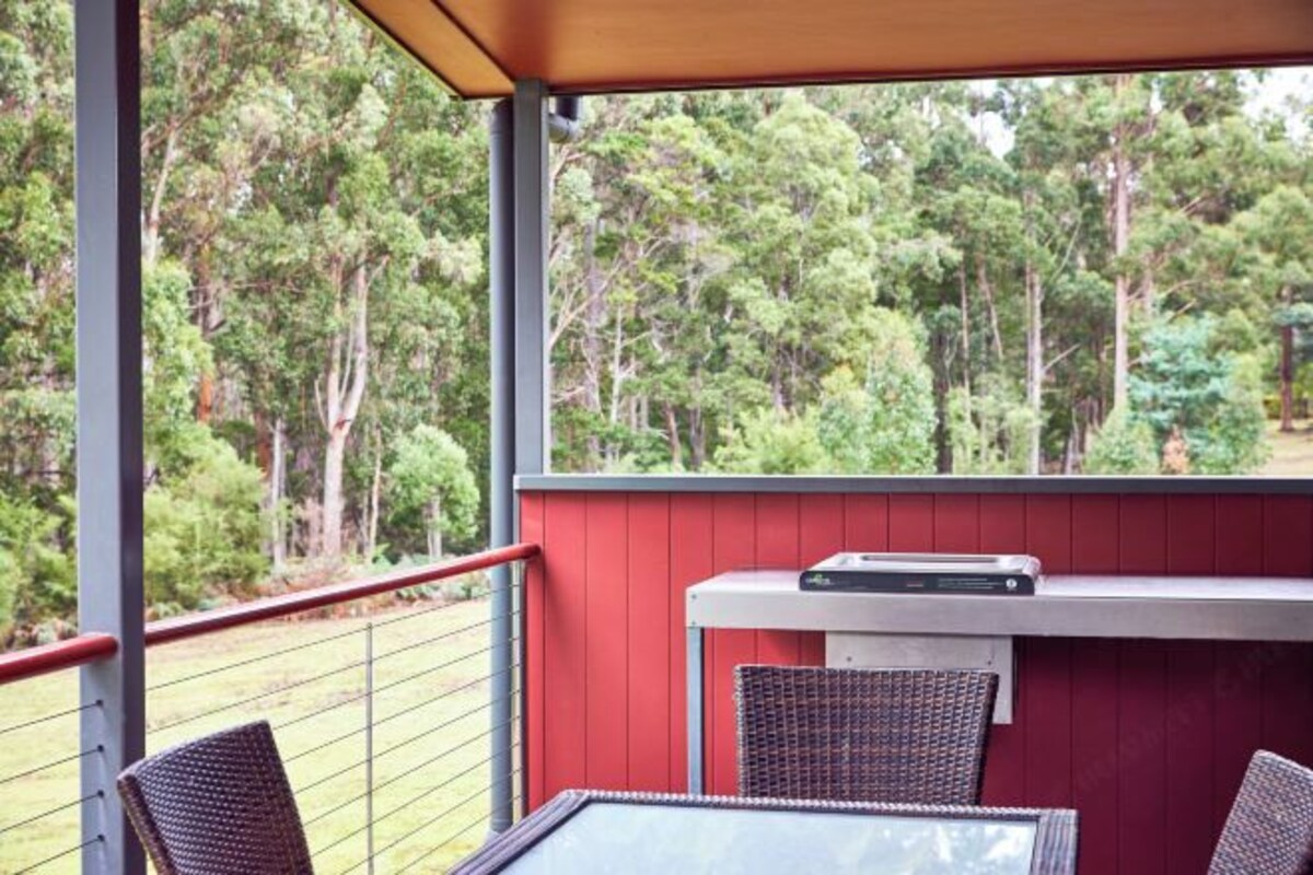 A balcony with wicker furniture, a small table, and a built-in heater.