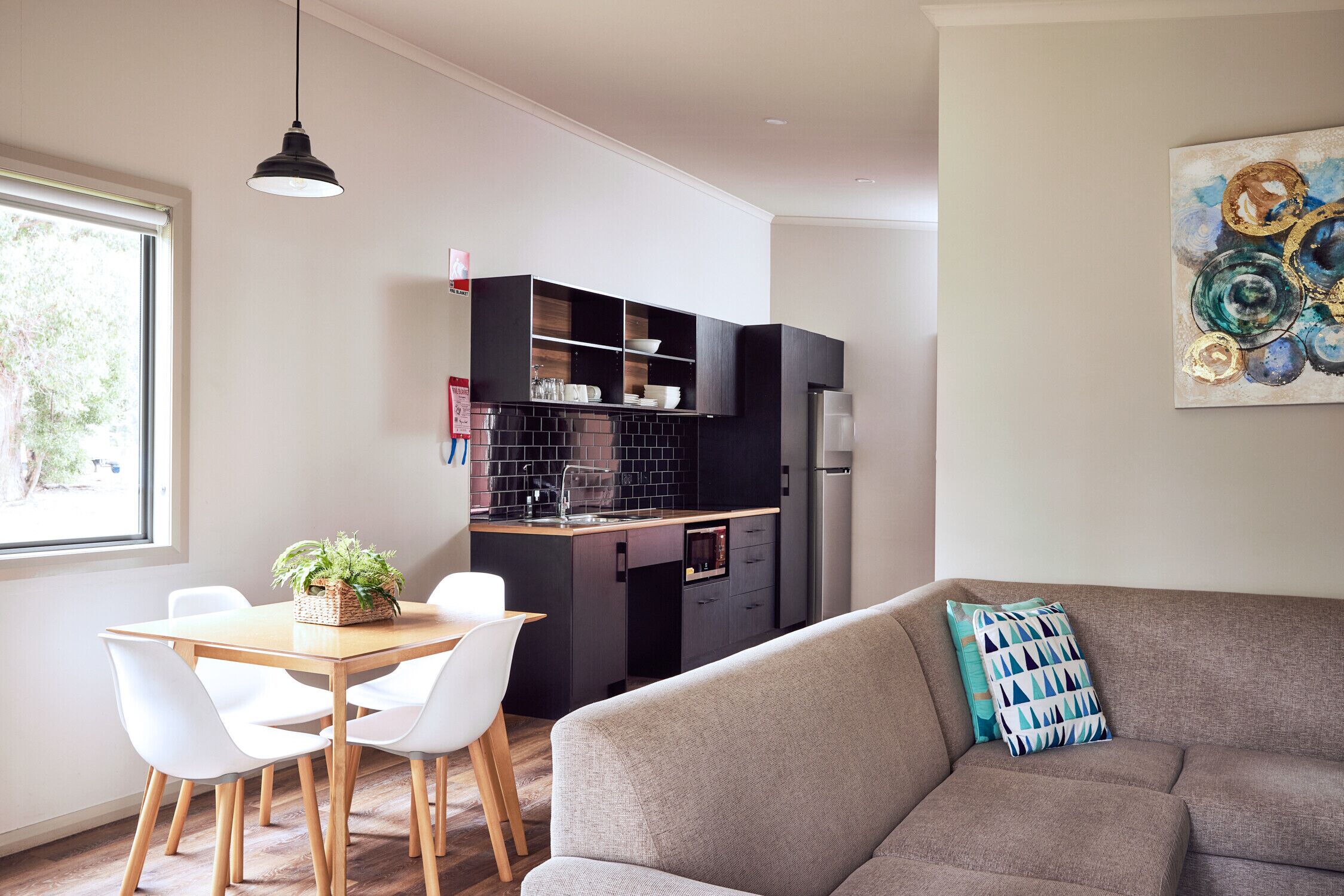 A modern living space with a dining area, kitchen, and a sofa with a patterned pillow.