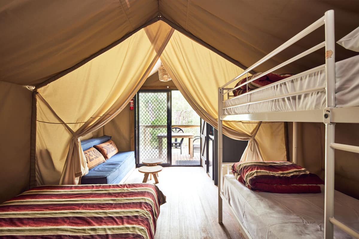Eine Zelthütte mit zwei Etagenbetten, einem kleinen Tisch und einer Schlafcouch.