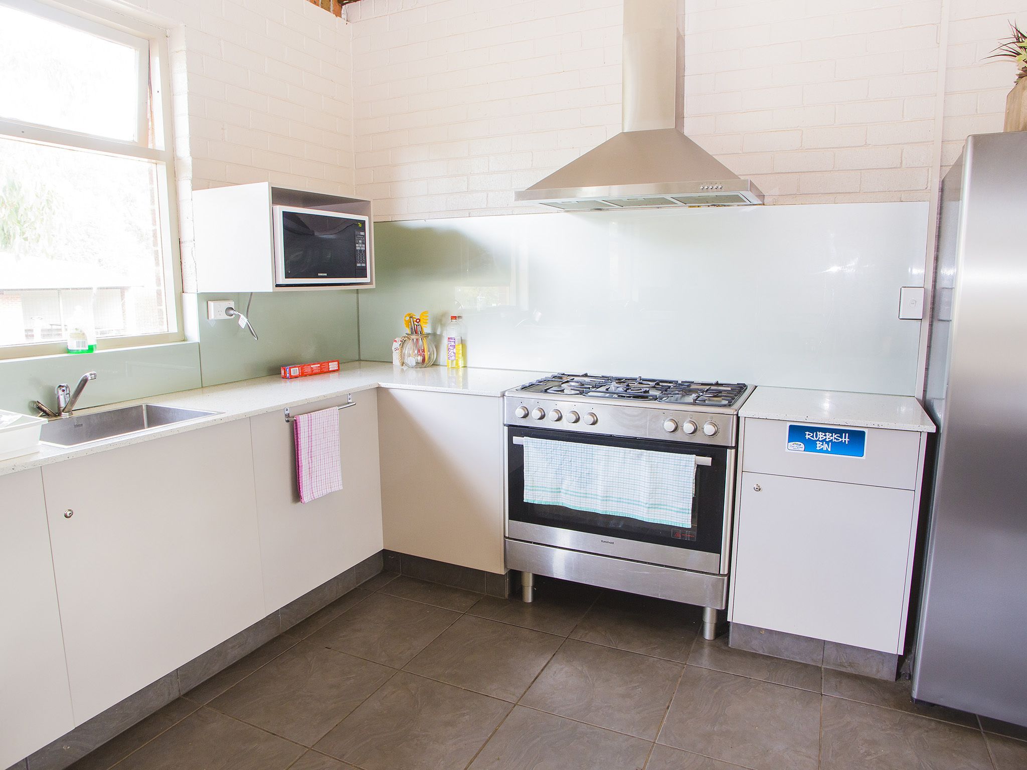 A compact kitchen with a stove, oven, microwave, and a sink.