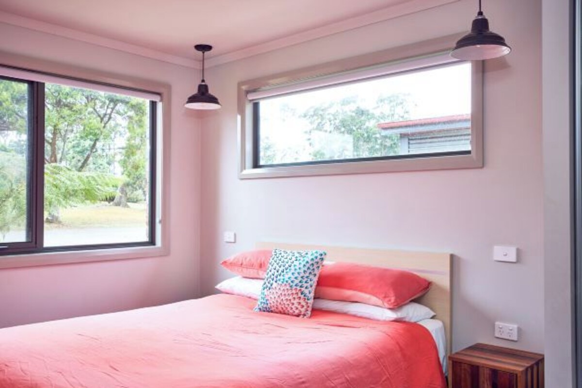 A bedroom with a bed, two windows, and a nightstand.