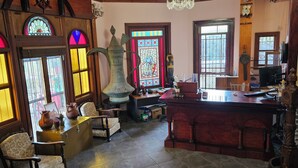 Una habitación con barra de madera, un jarrón grande y una ventana de vitral.