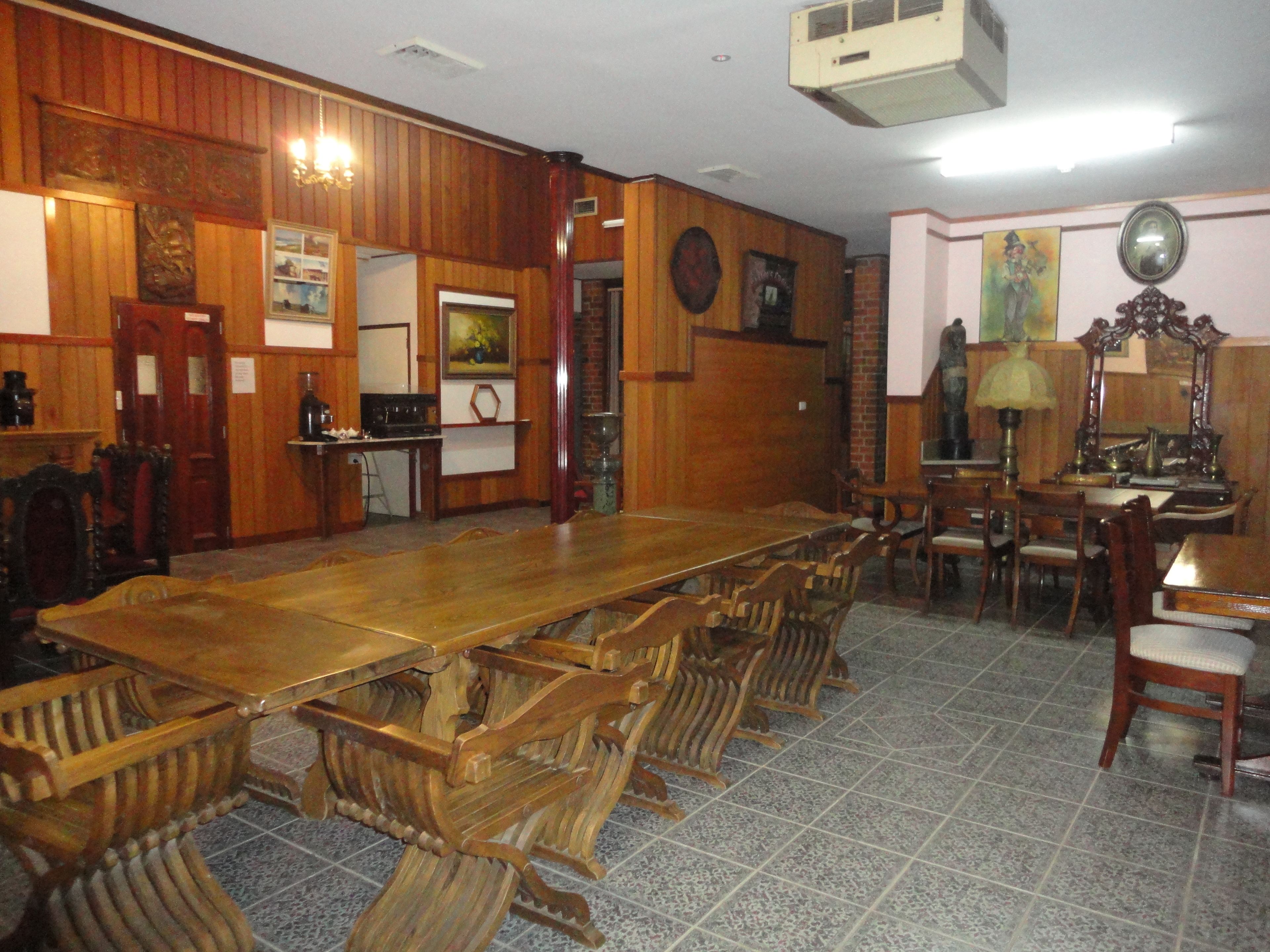 A dining area with a long wooden table and chairs, a kitchen area with a stove and refrigerator, and a tiled floor.