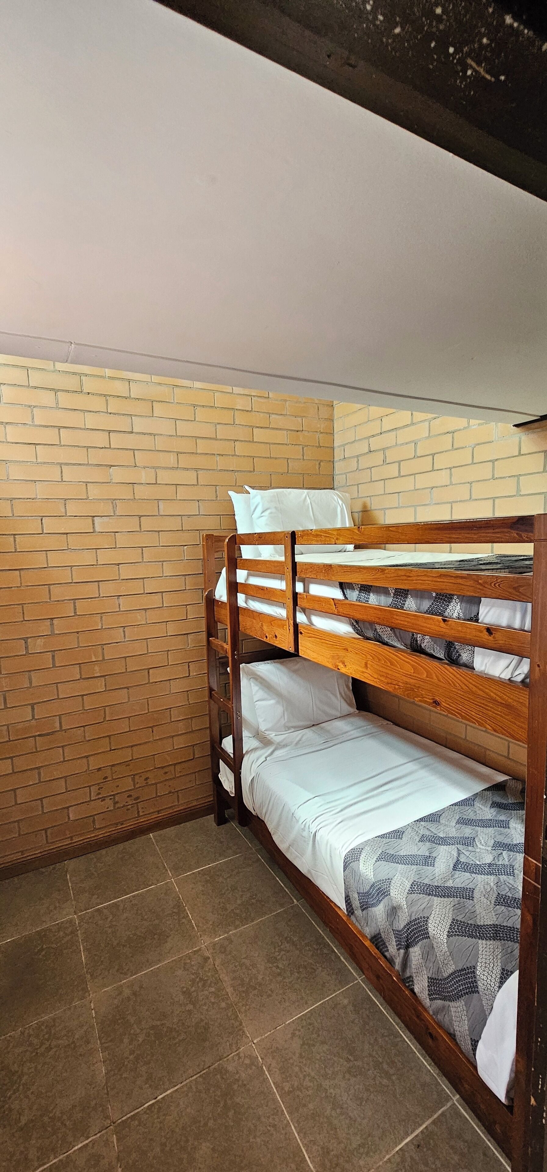 A bunk bed in a room with a brick wall and tiled floor.