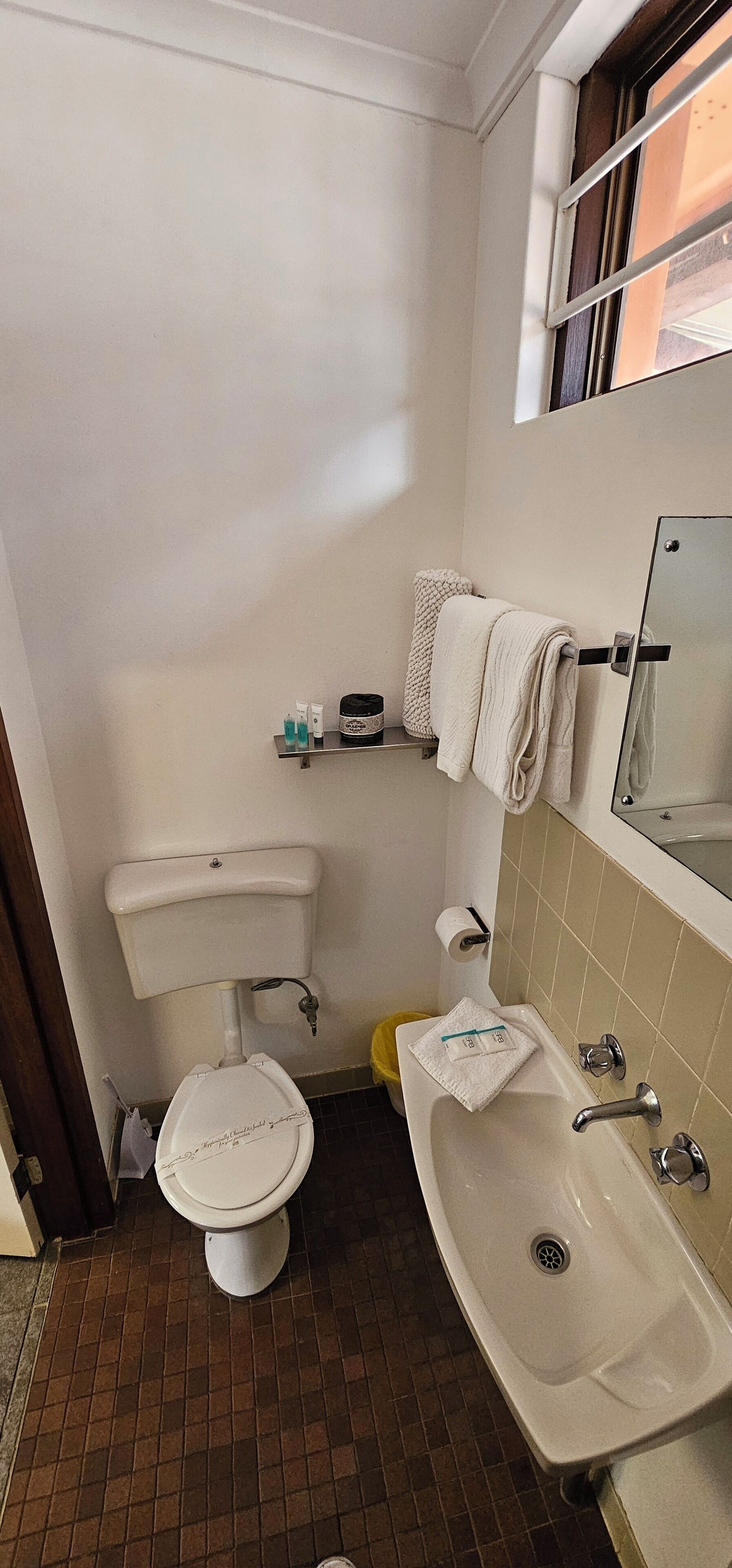A small bathroom with a toilet, sink, and a window.