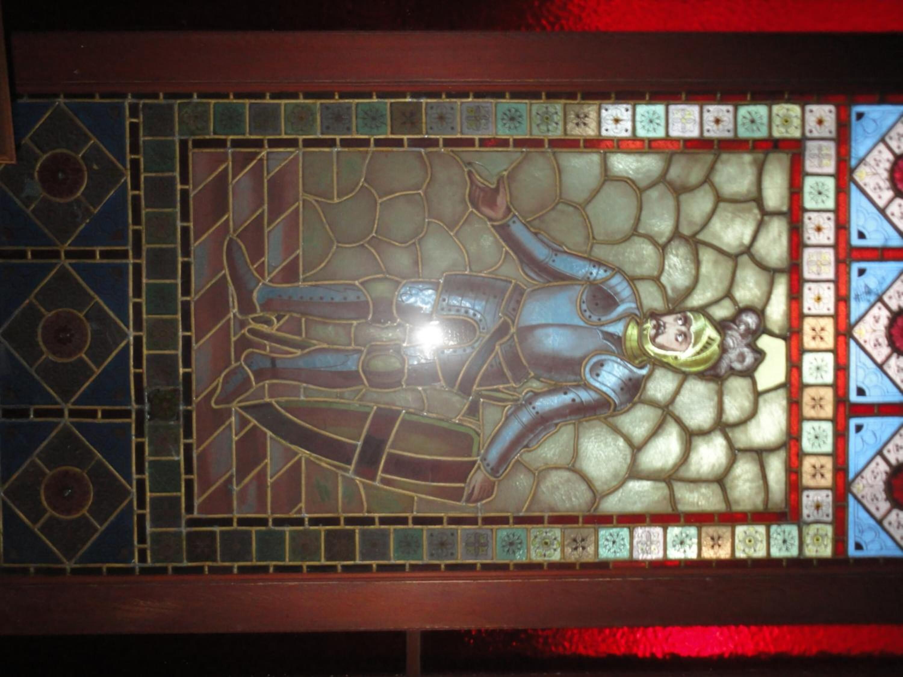 Una ventana de vitral con un diseño geométrico y una figura central.