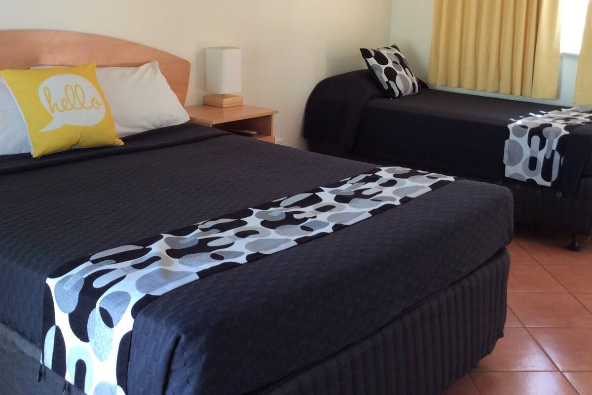 Une chambre d’hôtel avec deux lits, une table de chevet, une lampe et un tableau encadré au mur.