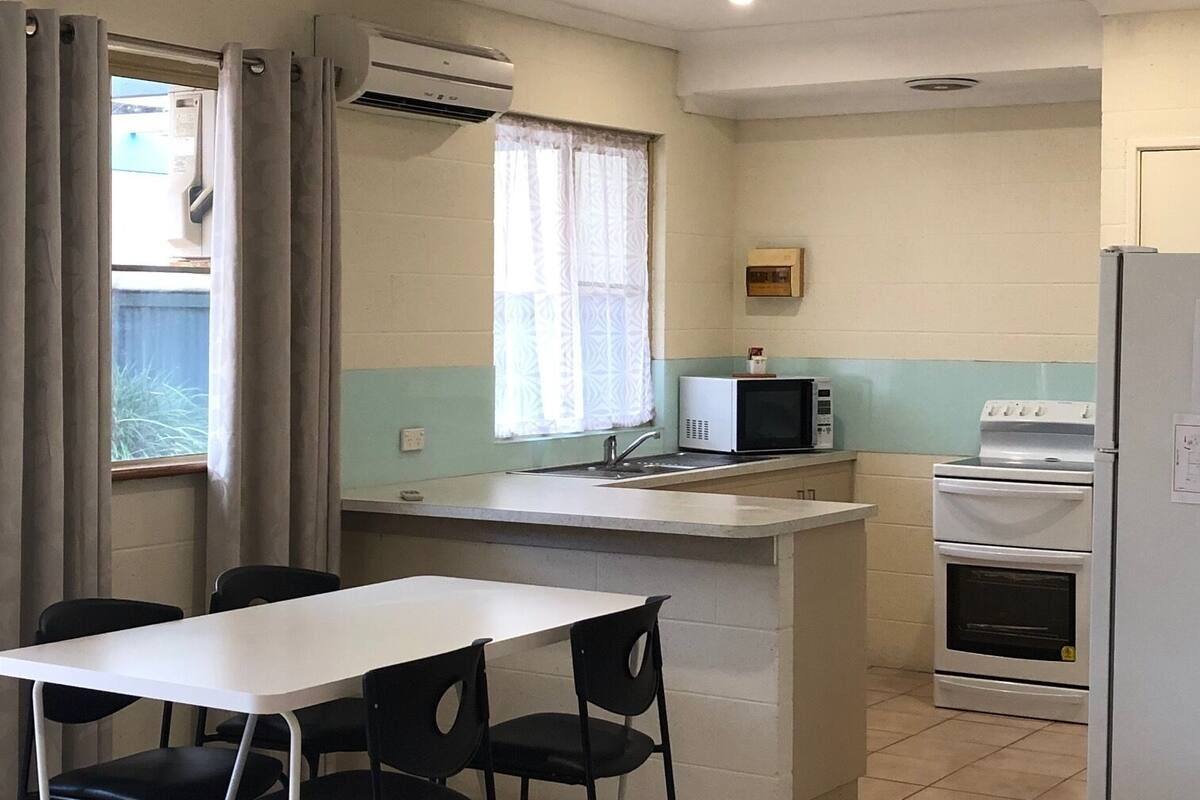 Une cuisine compacte avec un coin repas, comprenant un réfrigérateur blanc, un four à micro-ondes, une cuisinière et un évier.