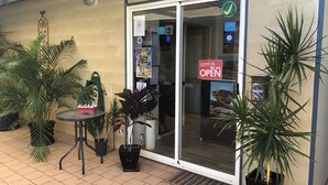 Una oficina con puerta de vidrio, un cartel que indica que está abierta y varias plantas en macetas.