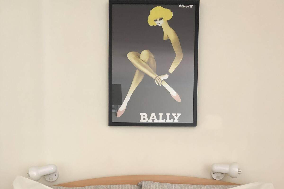 Une chambre d’hôtel avec un lit, des oreillers et une œuvre d’art encadrée accrochée au mur.
