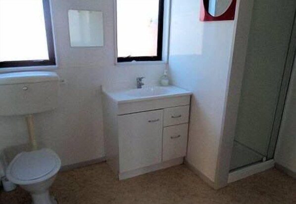 A small, clean bathroom with a toilet, sink, and shower.
